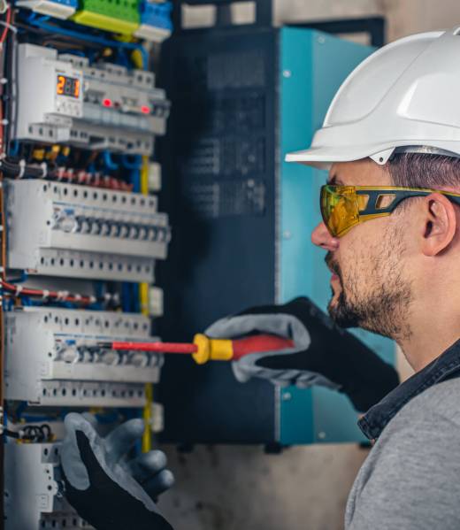 Man, an electrical technician working in a switchboard with fuses. Installation and connection of electrical equipment.