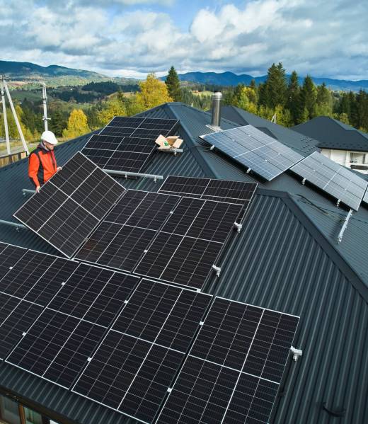 Builders building photovoltaic solar module station on roof of house. Men electricians in helmets installing solar panel system outdoors. Concept of alternative and renewable energy. Aerial view.